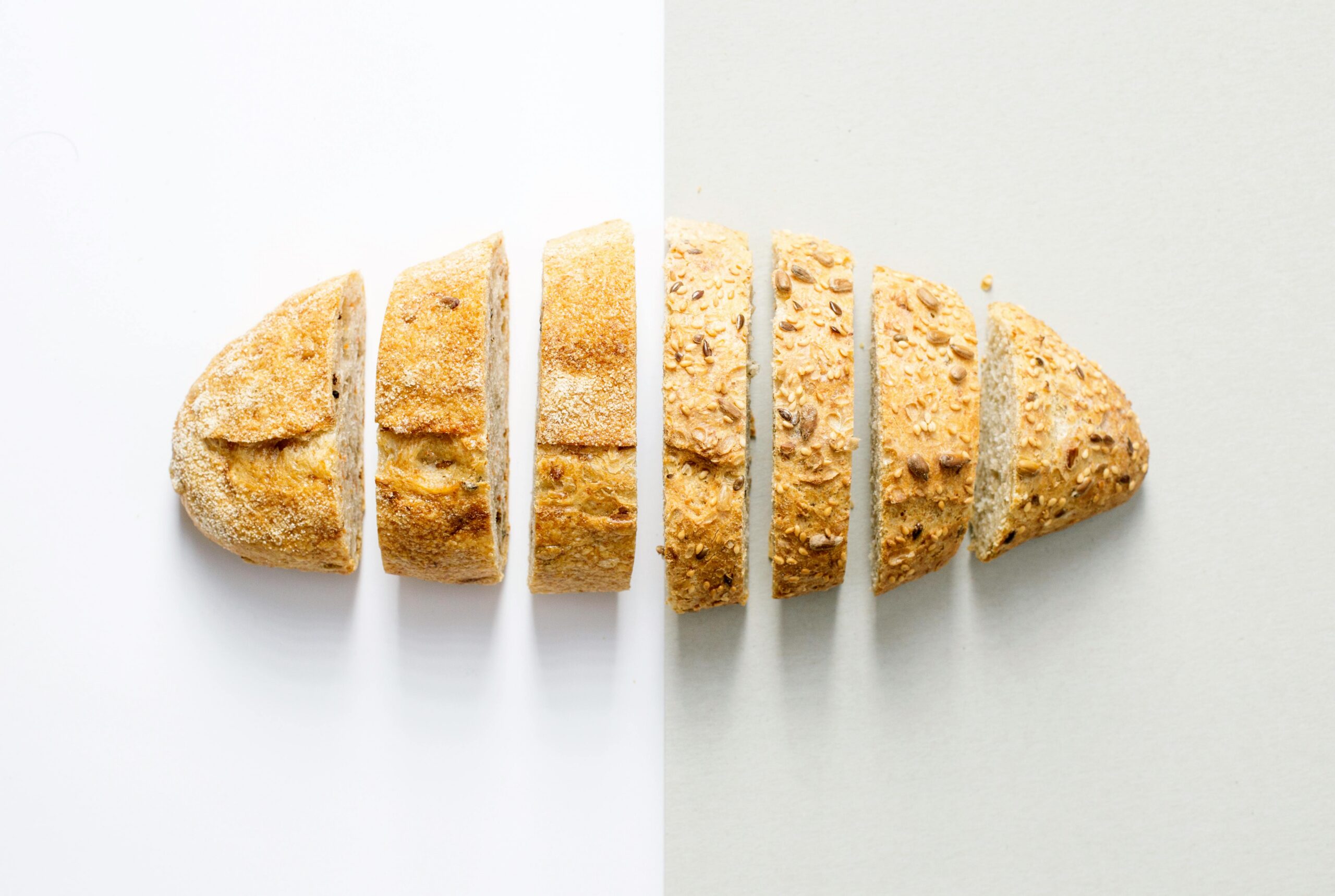 Freshly baked whole wheat bread sliced on a white background, showcasing its homemade texture.